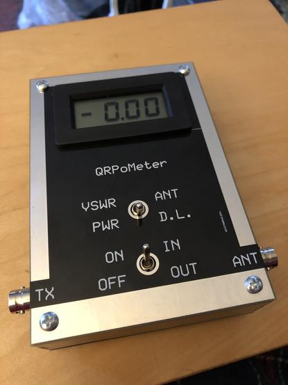 A fully assembled "QRPoMeter" amateur radio power meter in the "on" position. The digital display shows "-0.00" watts of forward power, since the unit is not connected to a transmitter which is transmitting.