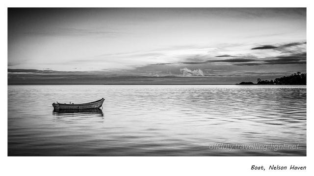 Photo of a small dinghy on calm water with a clear sky behind