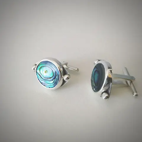a pair of silver cufflinks with round iridescent stone