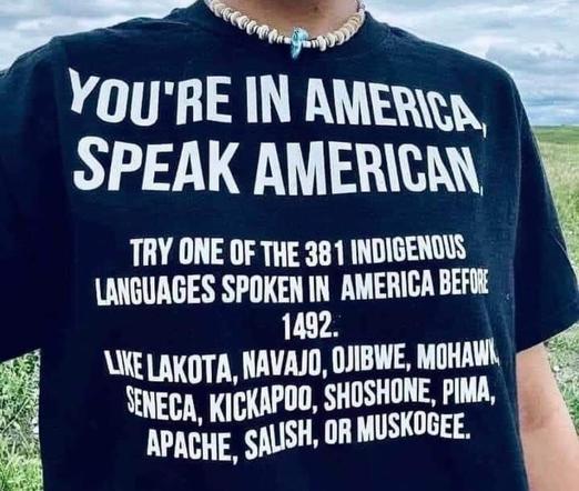 Photo of a T-shirt. Text on shirt reads,

YOU'RE IN AMERICA, SPEAK AMERICAN

TRY ONE OF THE 381 INDIGENOUS LANGUAGES SPOKEN IN AMERICA BEFORE 1492.

LIKE LAKOTA, NAVAJO, OJIBWE, MOHAW SENECA, KICKAPOO, SHOSHONE, PIMA, APACHE, SALISH, OR MUSKOGEE.