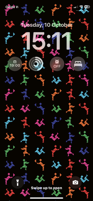 Screenshot van het homescreen van mijn telefoon, met de tijd (15:11) en datum (Tuesday, 10 October), een aantal widgets en als achtergrond de artwork van Bobbie, het nieuwe album van Pip Blom. Het artwork bestaat uit abstracte figuurtjes in roze, donkerblauw, groen, oranje, rood en lichtblauw in een herhalend patroon