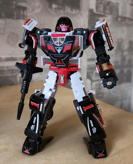 Crasher in robot mode with all stickers applied. The stickers move her deco closer to the original Gobot toy design, while also embellishing with lashings of technical detail such as applying a Chrome finish to vents and wheel trims.

If you magnify this image on her face you'll see some of the tiniest stickers ever applied to give her face a touch more of that original look, narrowing her mouth/jaw and adding pointed mask lines beneath her eyes.