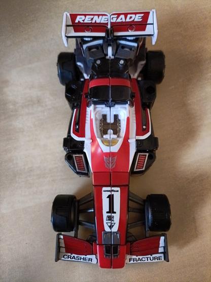 Crasher in F1 race car mode, covered with sticker detail, seen from directly overhead. Notable features are the word Renegade on her rear spoiler and her names on her forward fins.