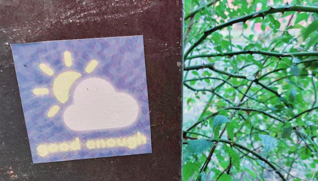 Baum-Äste mit grünen Blättern. Daneben ein Schild mit blauem Aufkleber, auf dem eine Sonne abgebildet ist, die hinter einer weißen Wolke hervorstrahlt. Darunter steht: good enough.