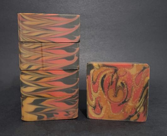 On the Left, four bars of soap stacked on their side and showing the tops, colored with red, yellow, orange and black to look like flames. The right is showing the side of the bar.