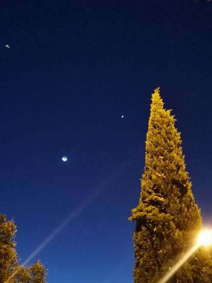 Se observa una diminuta luna cerca del centro de la foto, más arriba y a la derecha un punto luminoso menor que la luna es venus.