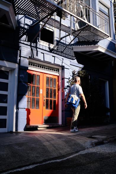 A pedestrian passing a bright orange door.