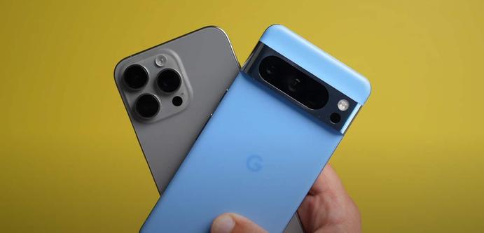 Eine Hand hält die Rückseiten eines titangrauen iPhone 15 Pro Max und eines hellblauen Google Pixel 8 Pro in die Kamera. Foto (c) MacRumors.