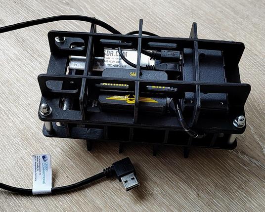 FlightBox hardware assembly, consisting of black cardboard spares holding together a powerbank, a Raspberry Pi Zero, a USB hub with an RTL-SDR and a soundcard stick, and a GNSS module.