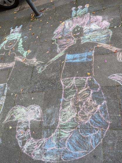 Bunte Kreidezeichnung von Nixen auf dem Bürgersteig. Mermaids drawn on the sidewalk with colorful chalk.