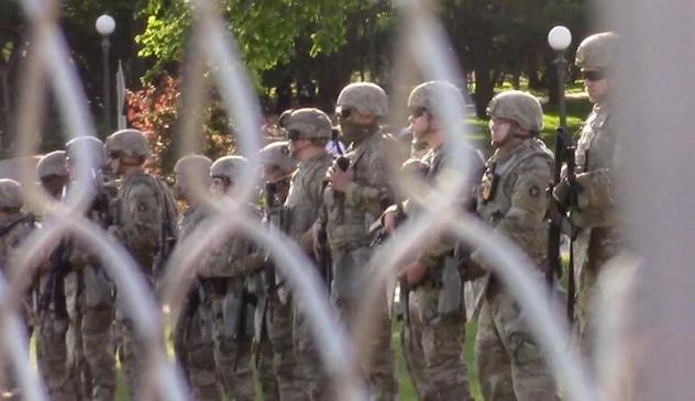 A photograph of soldiers through a wire fence
