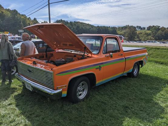 Photo of a vintage orange Chevy Silverado with the hood open.