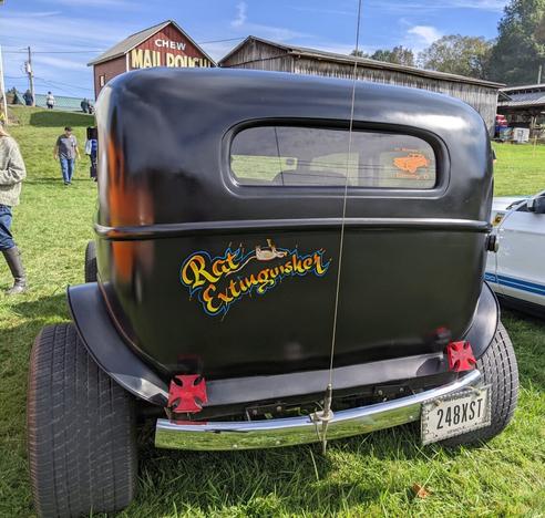 Back view of the vintage black hot rod car with 'Rat Extinguisher' painted on the back.