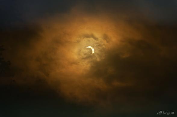 View of the annular solar eclipse, seen through a partly cloudy sky.
