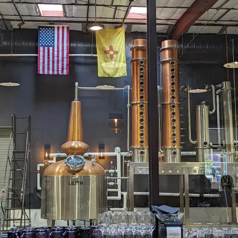 One pot still and two column stills beneath the American and New Mexican flags.