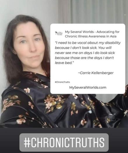 Carrie is wearing black satin pajamas. She is sitting in bed next to a sign that says:

"I need to be vocal about my disability because I don't look sick. You will never see me on days I do look sick because those are the days I don't leave my bed." Carrie, MySeveralWorlds.com