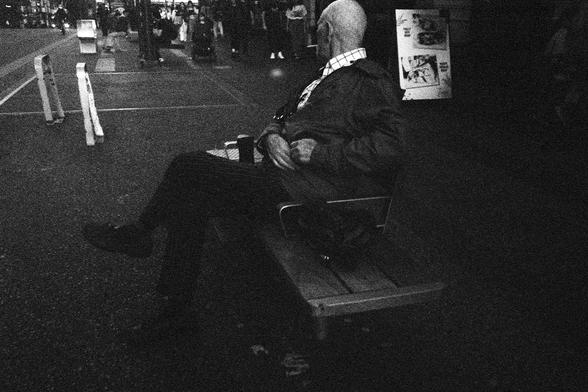 A smoker sits, peering down the street.
