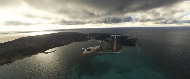 Cessna Citation Longitude taking off, looking back at Shimoji Island, Japan. The sun is rising on the left side, just behind the plane.