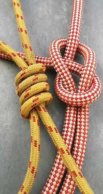 Un nœud de chaise sur corde 12 mm rouge et blanche au côté d'un nœud de pêcheur double sur corde 7 mm jaune et rouge sur un fond gris zinc