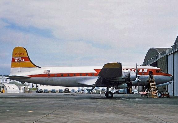 The 4 engin prop plane is stationed near hangers with a pair of stairs leading the the forward door.