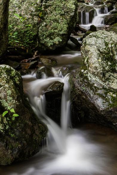 Water cascades over greenish rocks.