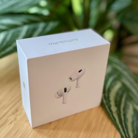 Apple AirPods Pro 2nd generation box sitting on table in front of plant