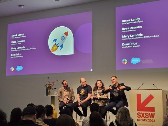 Four panelists seated in front of a screen with their names projected on it: Derek Laney, Ross Dawson, Mary Lemonis, and Dom Price.