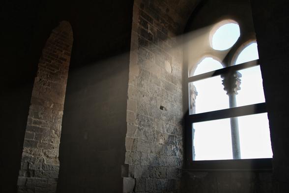 Lichtstrahlen scheinen durch ein Fenster in das steinige Castello di Naro.