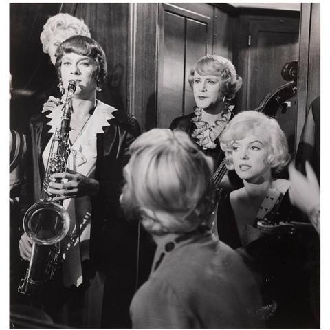 Still from Some Like it Hot. Tony Curtis (playing a saxophone) & Jack Lemmon (playing a double bass) dressed as women behind Marilyn Monroe.