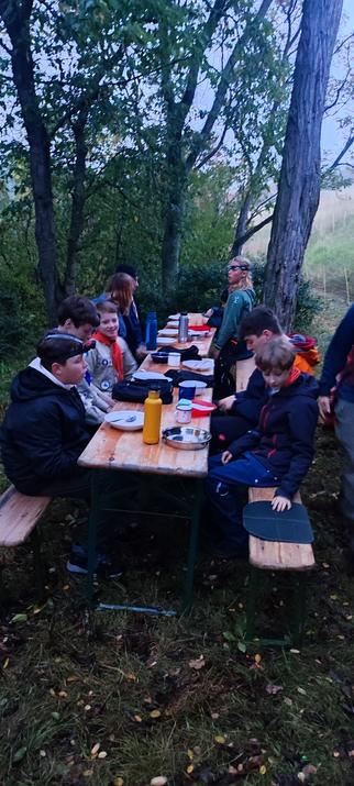 Die Pfadfinder sitzen an der Bank und warten auf das Abendbrot.