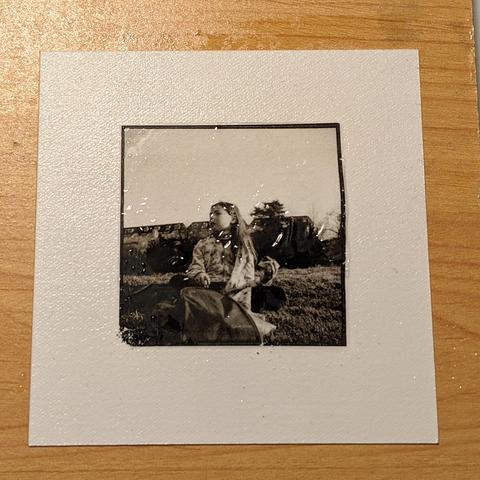 Photo en noir et blanc d'une jeune fille en train de goûter dans le parc des Buttes Chaumont. La photo a été déposée sur une papier Fabriano avec la technique du "ink lift print".