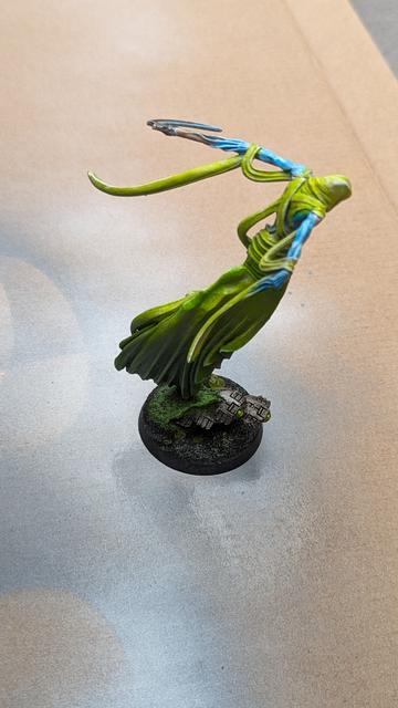 Picture of the C'Tan Shard of the Nightbringer, eerily green clothes, light blue skin, taken from above and behind his right shoulder