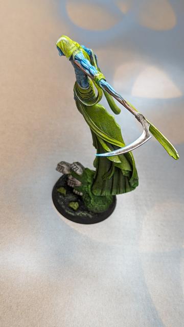 Picture of the C'Tan Shard of the Nightbringer, eerily green clothes, light blue skin, taken from above  his left shoulder
