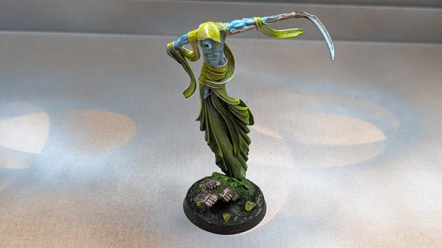 Picture of the C'Tan Shard of the Nightbringer, eerily green clothes, light blue skin, taken from above in the front