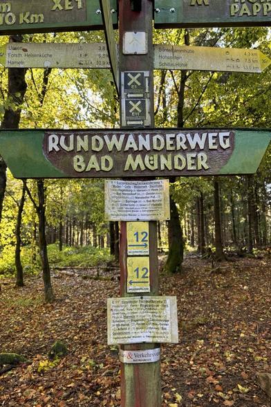 Ein Wegweiser mit vielen Orts- und Entfernungsangaben. Außerdem mehrere Wanderwegzeichen u.a. E1 und E11.