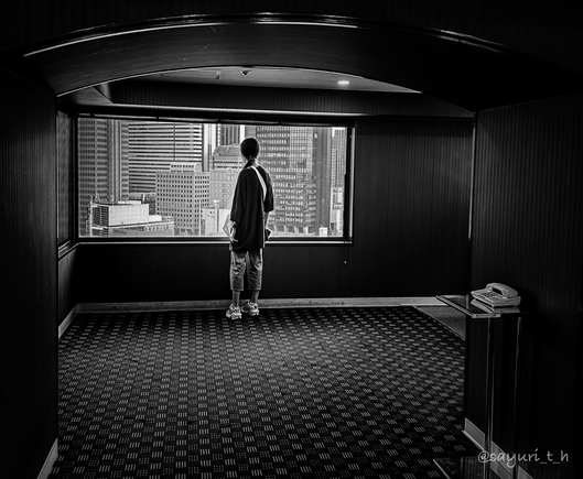 A girl looking at high rises through the window at elevator lobby