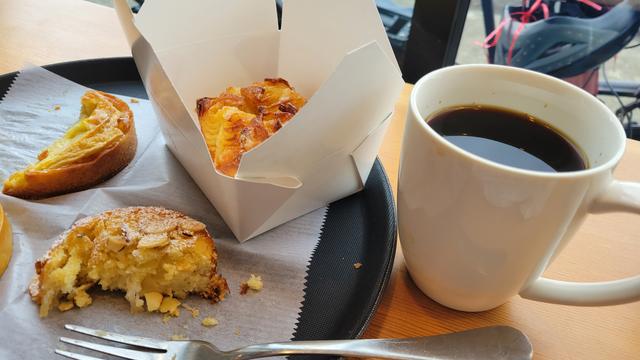 Photo of several pastries on a tray, two of them half eaten, next to a cup of coffee.