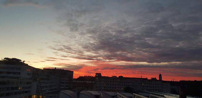 A sky lìne with red clouds being lit from the bottom by the rising sun.