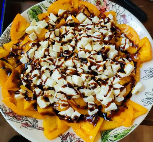 Sliced Orange Tomatoes with diced mozzarella cheese and heavily drizzled with a balsamic glaze.