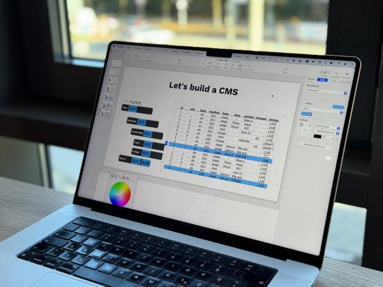 A MacBook screen showing a slide in Keynote. The headline is „Let‘s build a CMs“, below there‘s a content table with data rows for content.