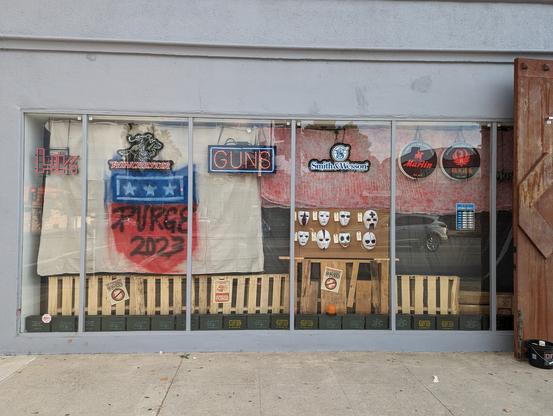 The window of a gun store, with a display themed for the move "The Purge"