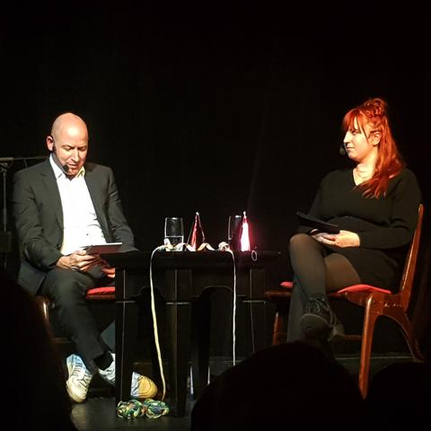 Martin Krist und Sarah Lippasson sitzen an einem Tisch bei der Lesung zum Jubiläum.