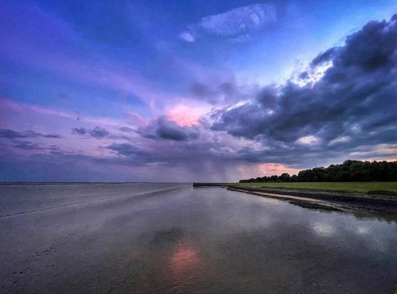 A colourful sunset with blue and violet colours on the wadden beach of Wilhelmshaven, Germany.