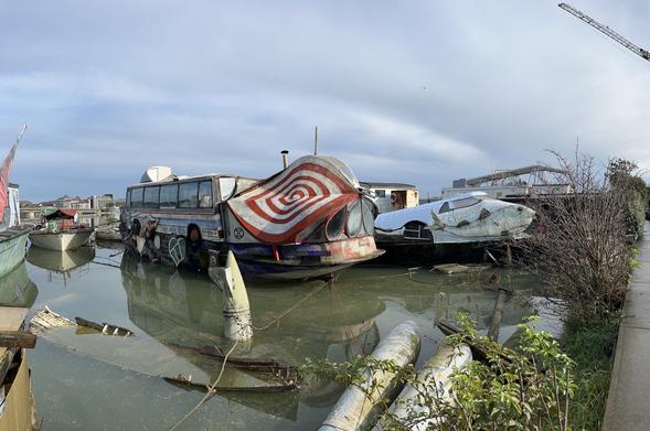 Houseboat or hippy art project? A fibreglass shell at the landward end looks like giant insect eyes, and the main body is a coach, still with wheels, sitting on the deck. Alas, “extinction rebellion” insignia.