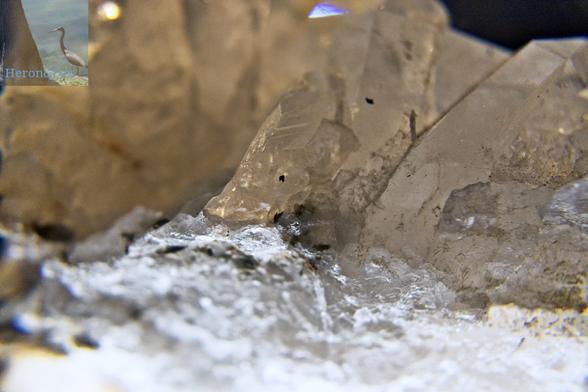 A close-in macro photograph of a white quartz crystal with gray flaws against the white crystal surface.