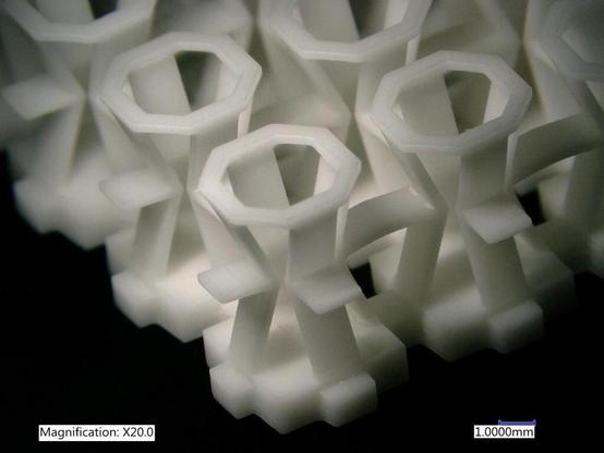Optical microscope image of an auxetic structure 3printed from ceramic material. The top layer is a matrix of thin octagons. Supporting struts zig-zag downward from these and interconnect to form a lattice. Original caption was: 3D-printed ceramic structures, magnified X20.
