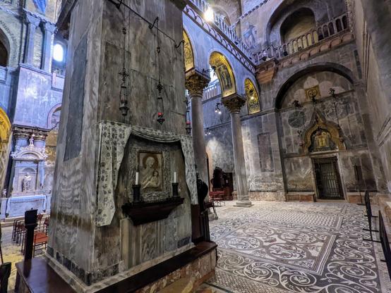 This is an interior corner of an old Italian basilica.  A very large pillar is in the foreground.  The ceilings are gilded.