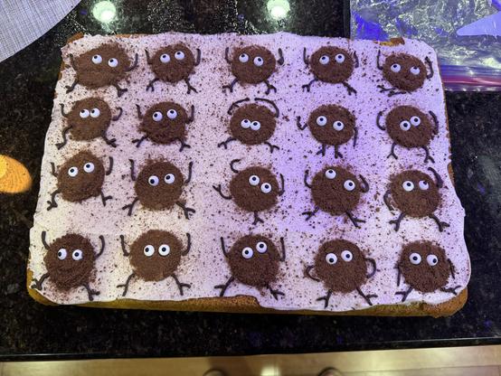 A pumpkin sheet cake with cream cheese frosting. There are 20 soot sprites made out of crumbled chocolate cookies with candy eyes and piped chocolate limbs. They’re all in different poses.