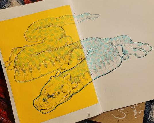 An open sketchbook with a marker and ballpoint pen drawing of a very long, serpentlike wyrm. The left page has a large yellow square of paper on it.