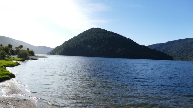 Image shows Lake Paringa on the West Coast of Te Wai Pounamu/South Island, The lake has the shape of a letter "C" when viewed on a map, the image shows one 'arm' of the C and the promontory that juts into the lake
